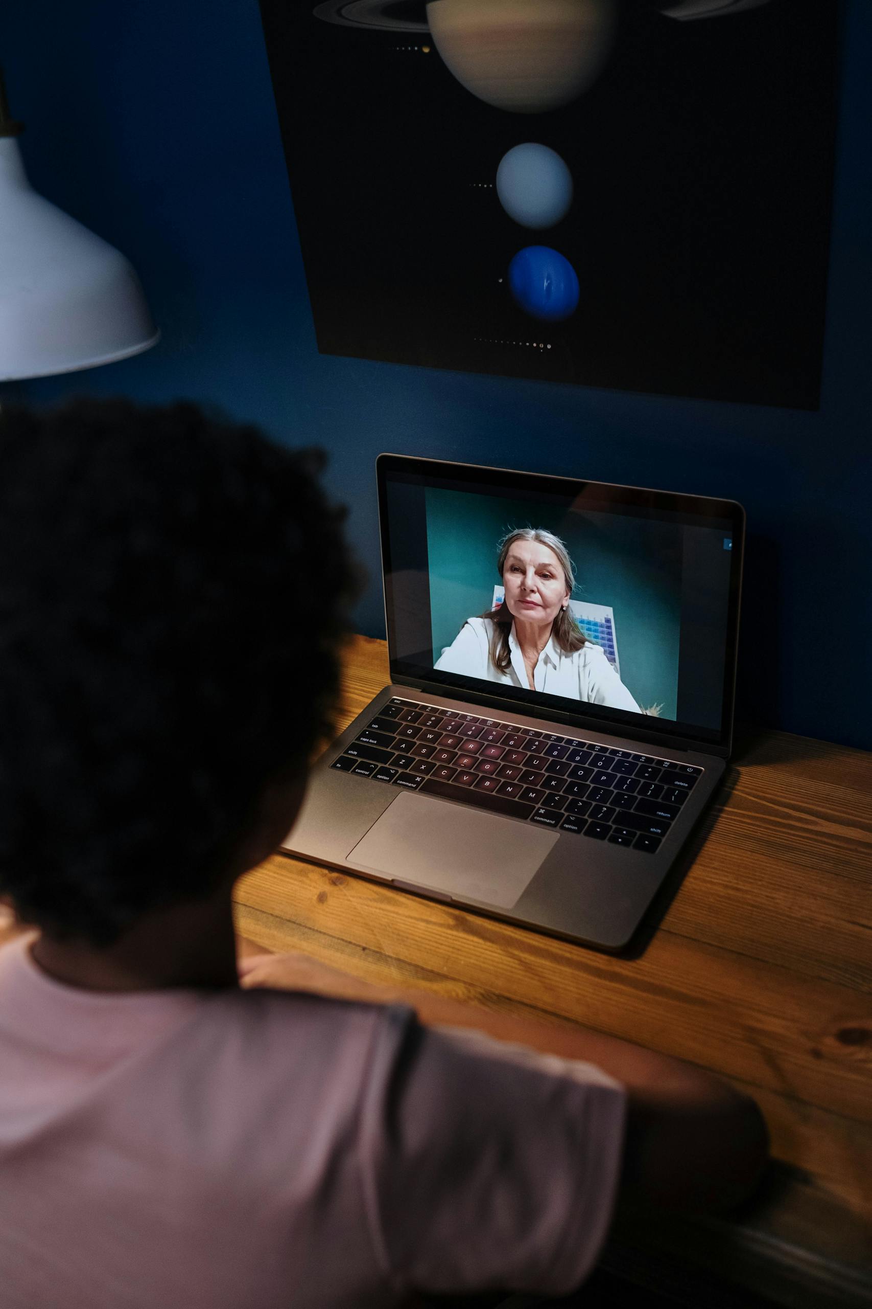 Teenager participates in an online learning session via laptop with a teacher on video call.